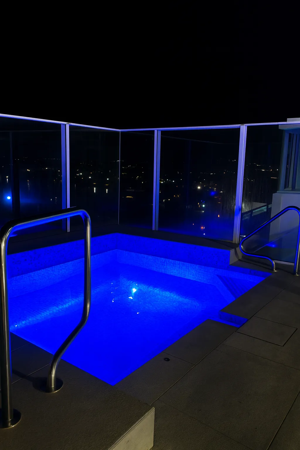 Rooftop spa lit blue at night overlooking Caloundra lights